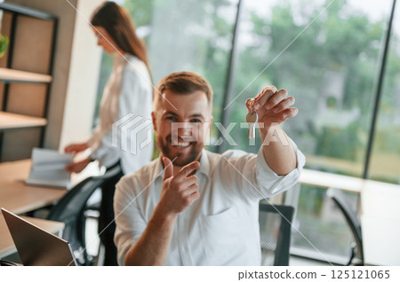 Holding keys for the new apartment. Man and woman are working in the modern office together 125121065