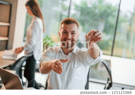 Holding keys for the new apartment. Man and woman are working in the modern office together 125121066