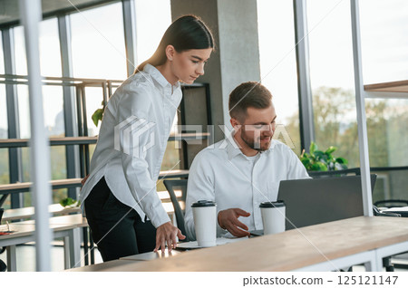 Using laptop. Man and woman are working in the modern office together 125121147