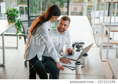 Using laptop. Man and woman are working in the modern office together 125121149