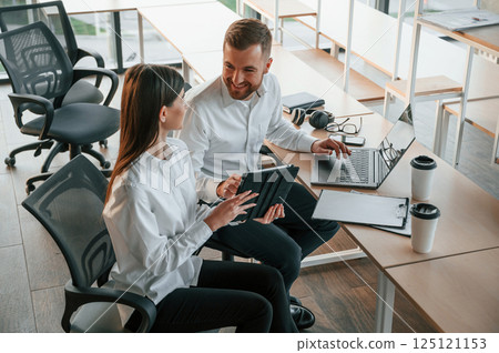 With graphic tablet and laptop. Man and woman are working in the modern office together 125121153