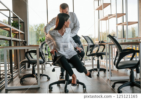 Having fun by riding the chair. Man and woman are working in the modern office together 125121165