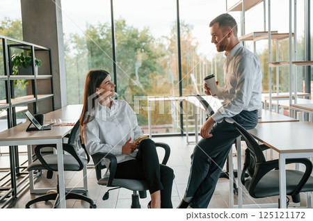 Having a break, talking, using smartphone. Man and woman are working in the modern office together Having a break, talking, using smartphone. Man and woman are working in the modern office together 125121172