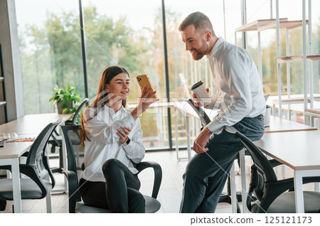 Having a break, talking, using smartphone. Man and woman are working in the modern office together 125121173