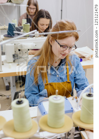 Three women seamstresses and fashion designers work in for sewing machines, clothing production. Three women seamstresses and fashion designers work in for sewing machines, clothing production. 125121479