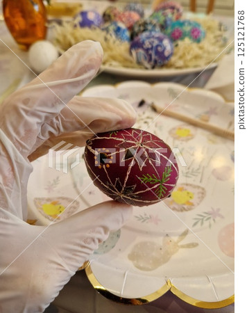 Easter egg crafted with traditional Ukrainian pysanka beeswax technique showcasing intricate folk patterns in a vibrant color palette during the spring festival 125121768