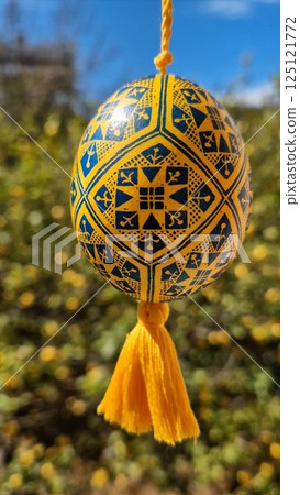 Traditional Ukrainian pysanka featuring national colors yellow and blue alongside beautiful Easter eggs in a vibrant setting 125121772