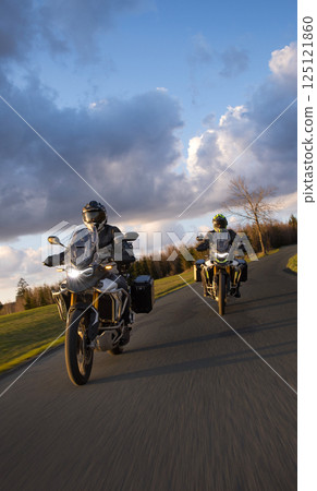 Drivers riding motorcycle on empty road during sunset, spring mountains 125121860