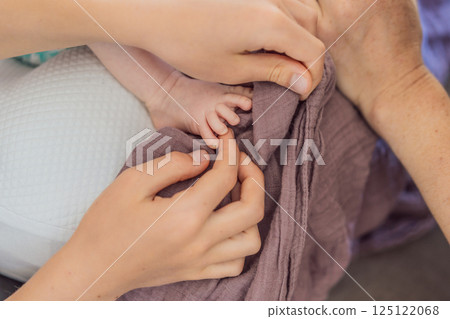 Mother and older son gently admiring the tiny foot of their newborn baby. Precious family bonding and sibling love concept 125122068