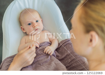 Mother and older son admiring their newborn baby in a cozy infant nest. Family bonding and sibling love concept 125122069