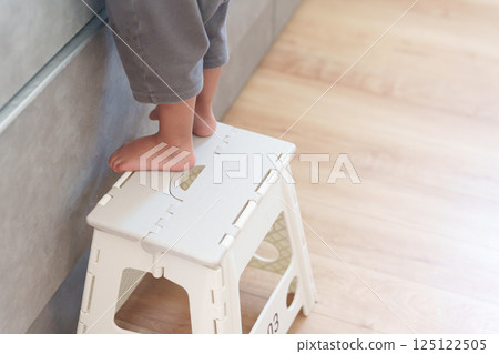 孩子站在廚房的踏腳凳上 125122505
