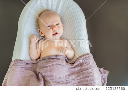 Newborn baby comfortably resting in a cozy baby nest. Safe and peaceful sleep concept for infants 125122560