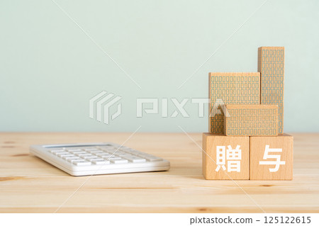 A block with the word "donation" written on it, a calculator, and a model of a real estate property A block with the word "donation" written on it, a calculator, and a model of a real estate property 125122615