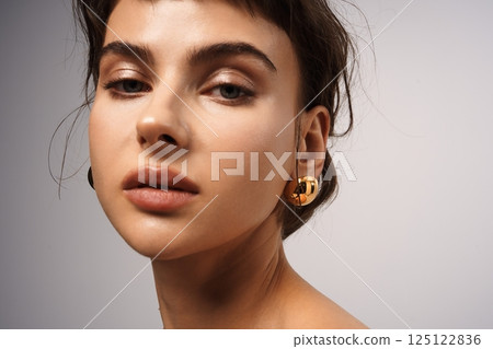 Elegant portrait of a woman with stylish earrings and natural makeup in a studio setting Elegant portrait of a woman with stylish earrings and natural makeup in a studio setting 125122836
