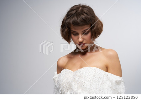 Elegant model showcases stunning white gown in a minimalist studio setting during a fashion event 125122850