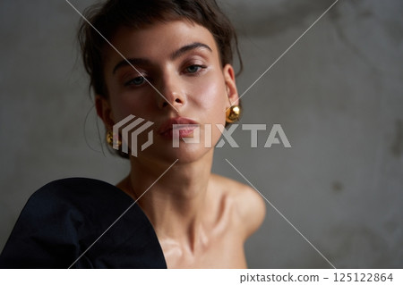 Model poses in minimalist setting with dramatic lighting and elegant accessories in a contemporary studio 125122864