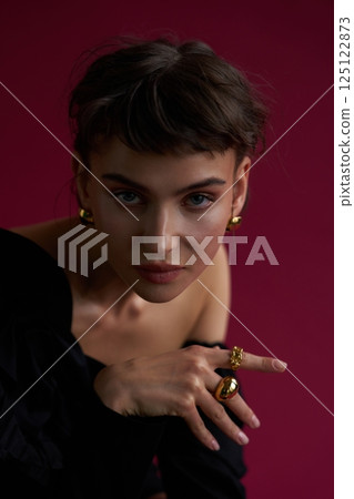 Fashion model showcasing elegant jewelry against a rich background in a studio setting 125122873