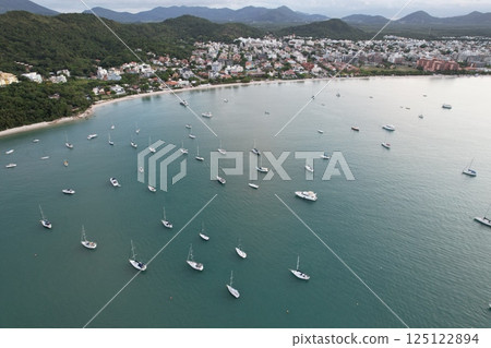 Beautiful coastal view of boats anchored in serene waters near a vibrant village 125122894