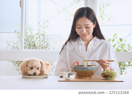 A woman enjoying a meal with her dog A woman enjoying a meal with her dog 125123268