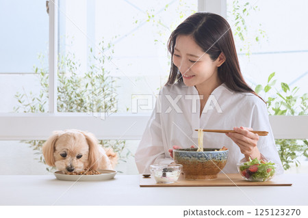 A woman enjoying a meal with her dog A woman enjoying a meal with her dog 125123270
