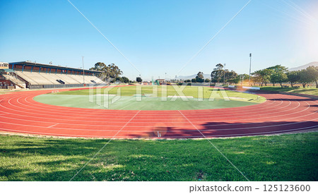 Sport, fitness and stadium track for running, outdoor and exercise landscape, blue sky and grass. Active, workout motivation and run for healthy life and sports view sun flare with cardio. Sport, fitness and stadium track for running, outdoor and exercise landscape, blue sky and grass. Active, workout motivation and run for healthy life and sports view sun flare with cardio. 125123600