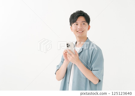 A young man operating a smartphone 125123640