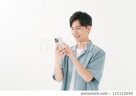 A young man operating a smartphone 125123644