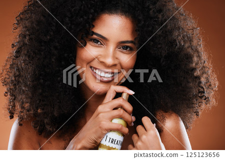 Beauty, hair care and portrait of a black woman with hair spray for natural hair routine in studio. Cosmetics, health and young African model with afro doing treatment with spray by brown background. 125123656