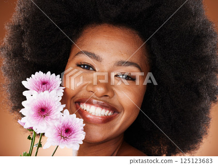 Black woman, face or afro hair with daisy flowers on studio background for gentle skincare, vibrant glow or organic dermatology. Zoom, portrait or happy smile beauty model with natural hair and plant 125123683
