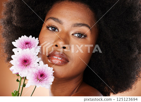 Flower, skincare and black woman natural hair in a studio portrait for beauty, cosmetics and eco friendly product promotion. Young african model face with daisy floral skin, hair care and self love 125123694