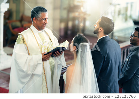 Wedding, couple and priest with a bible in church praying to God with a Christian pastor reading the holy book. Love, bride and groom say an oath for a faithful and spiritual marriage commitment 125123766