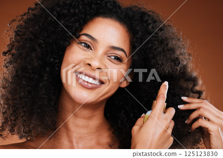 Black woman, spray and natural hair beauty for shine, healthy and curly texture care bottle. Hair care, happy and oil cosmetic protection product with confident girl model in brown studio. 125123830