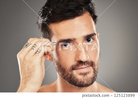 Face, portrait and tweezers with a man model plucking his eyebrows in studio on a gray background. Skincare, wellness and luxury with a handsome young male tweezing his eyebrow hair for grooming Face, portrait and tweezers with a man model plucking his eyebrows in studio on a gray background. Skincare, wellness and luxury with a handsome young male tweezing his eyebrow hair for grooming 125123899