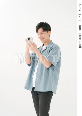 A young man operating a smartphone 125123925