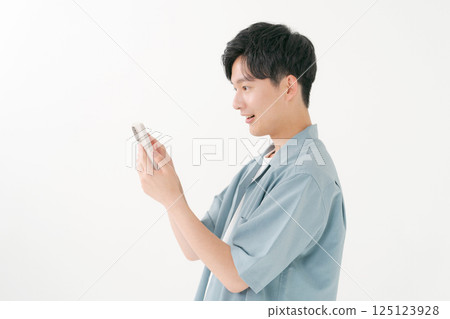 A young man operating a smartphone 125123928