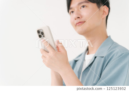 A young man operating a smartphone 125123932