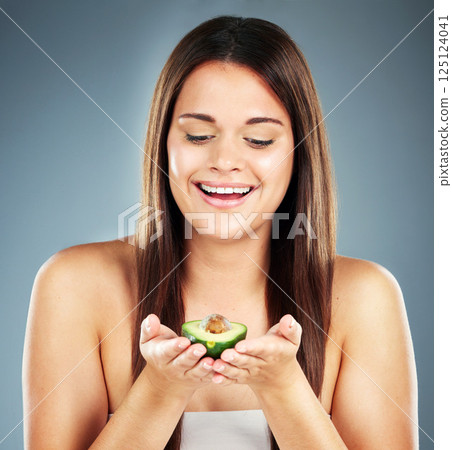 Woman, beauty and fruit with smile for skincare, nutrition or cosmetics against a studio background. Happy female holding avocado and smiling in satisfaction for natural, organic or healthy treatment Woman, beauty and fruit with smile for skincare, nutrition or cosmetics against a studio background. Happy female holding avocado and smiling in satisfaction for natural, organic or healthy treatment 125124041
