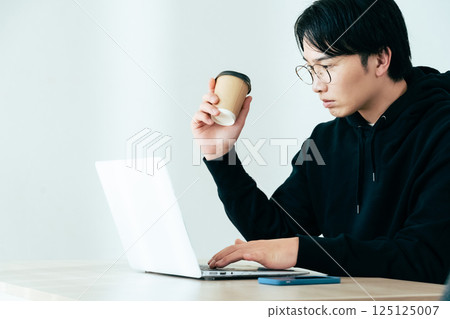 年輕人邊喝咖啡邊看電腦 125125007