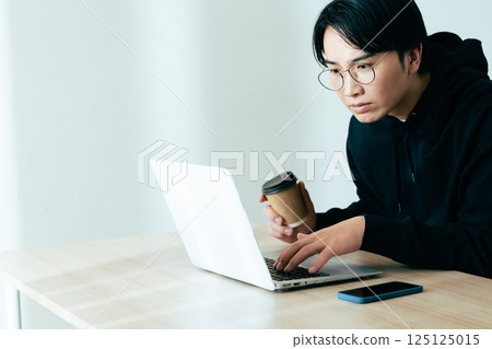 年輕人邊喝咖啡邊看電腦 125125015