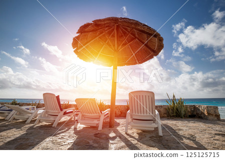 Caribbean beach with grass umbrellas and beds 125125715