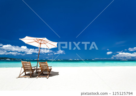 Sun umbrellas and wooden beds on tropical beach 125125794