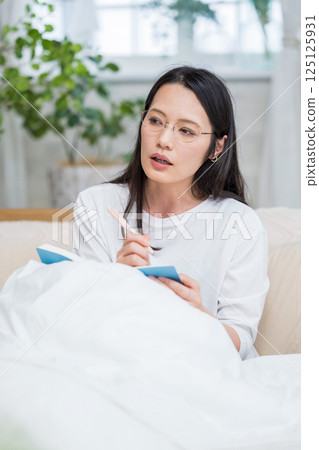 戴眼鏡的女人在床上看著筆記本思考日記 |健康生活方式圖像 |幸福女孩 |福利 125125931