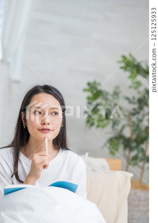 戴眼鏡的女人在床上看著筆記本思考日記 |健康生活方式圖像 |幸福女孩 |福利 125125933