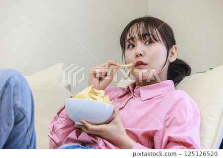 A woman eating sweets while watching TV 125126520