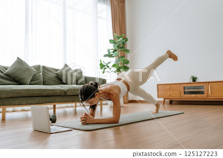 Young Asian woman in sportswear doing plank on training mat Young Asian woman in sportswear doing plank on training mat 125127223