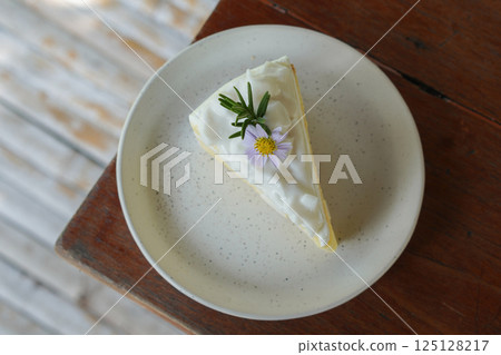 top view Coconut cake decorated with flowers and green leaves on a ceramic plate on a wooden table, blur bamboo floor background, food, dessert, copy space top view Coconut cake decorated with flowers and green leaves on a ceramic plate on a wooden table, blur bamboo floor background, food, dessert, copy space 125128217