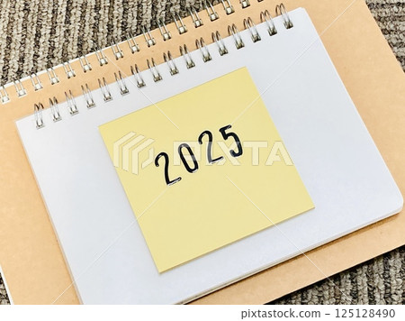 A yellow sticky note with the word 2025 written on it 125128490