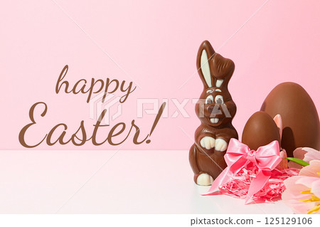 Easter, greeting inscription with chocolate eggs and a bunny, on a pink background Easter, greeting inscription with chocolate eggs and a bunny, on a pink background 125129106