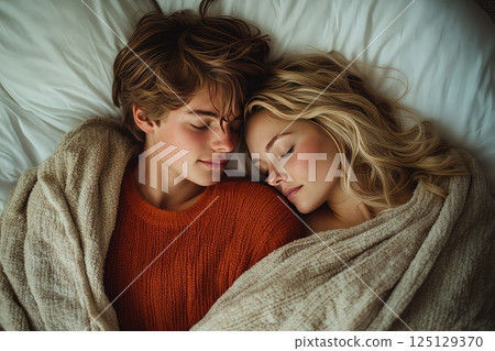 Close up of a young loving heterosexual couple sweet sleeping embracing each other. The couple shares a tender moment while sleeping, their intertwined bodies showcasing deep affection. 125129370