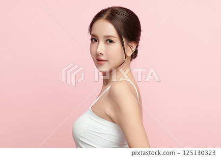 A beautiful young Asian woman with clean, fresh skin against a pink background. Skincare, facial treatment, cosmetology, beauty, and spa. An elegant portrait of an Asian woman. 125130323